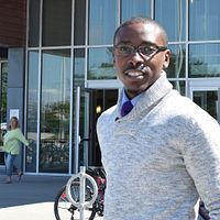 Picture of centennial college child and youth worker graduate kwesi johnson standing outside the progress campus library